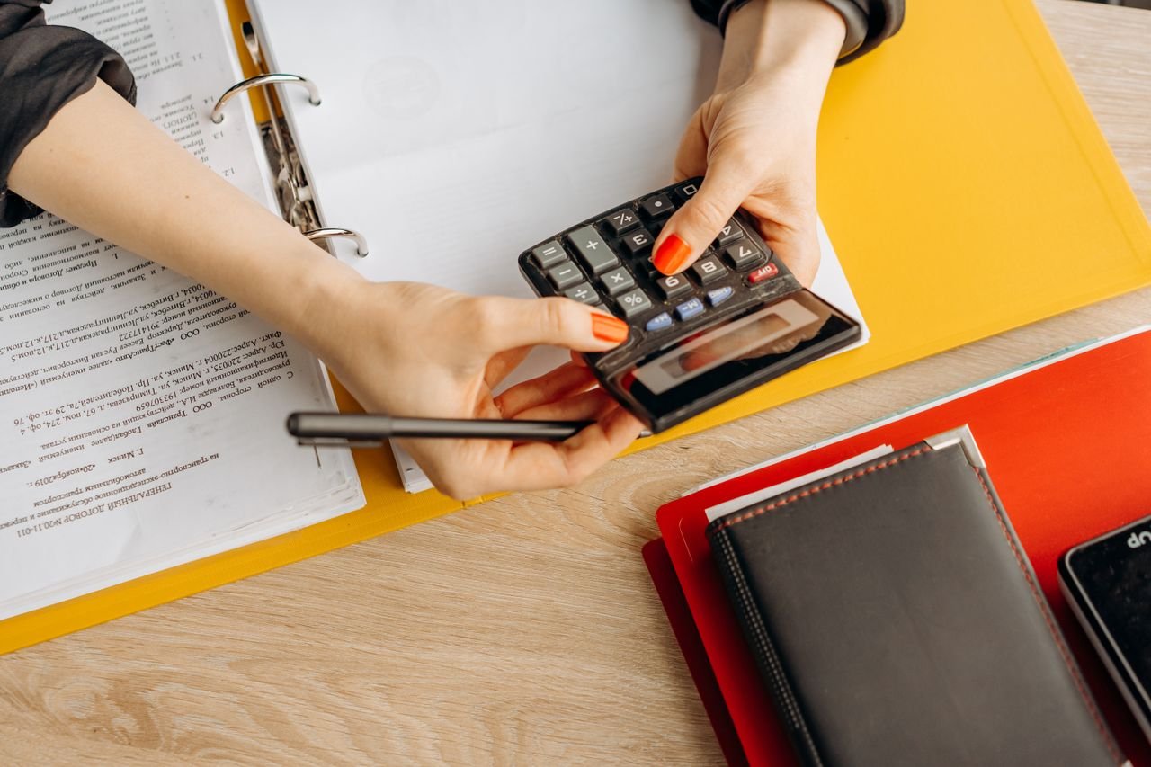 Services Hands using a calculator at a desk with documents and folders, ideal for finance or accounting themes.