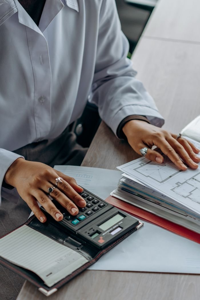 Services Accountant calculates finances with a calculator and documents on a desk.